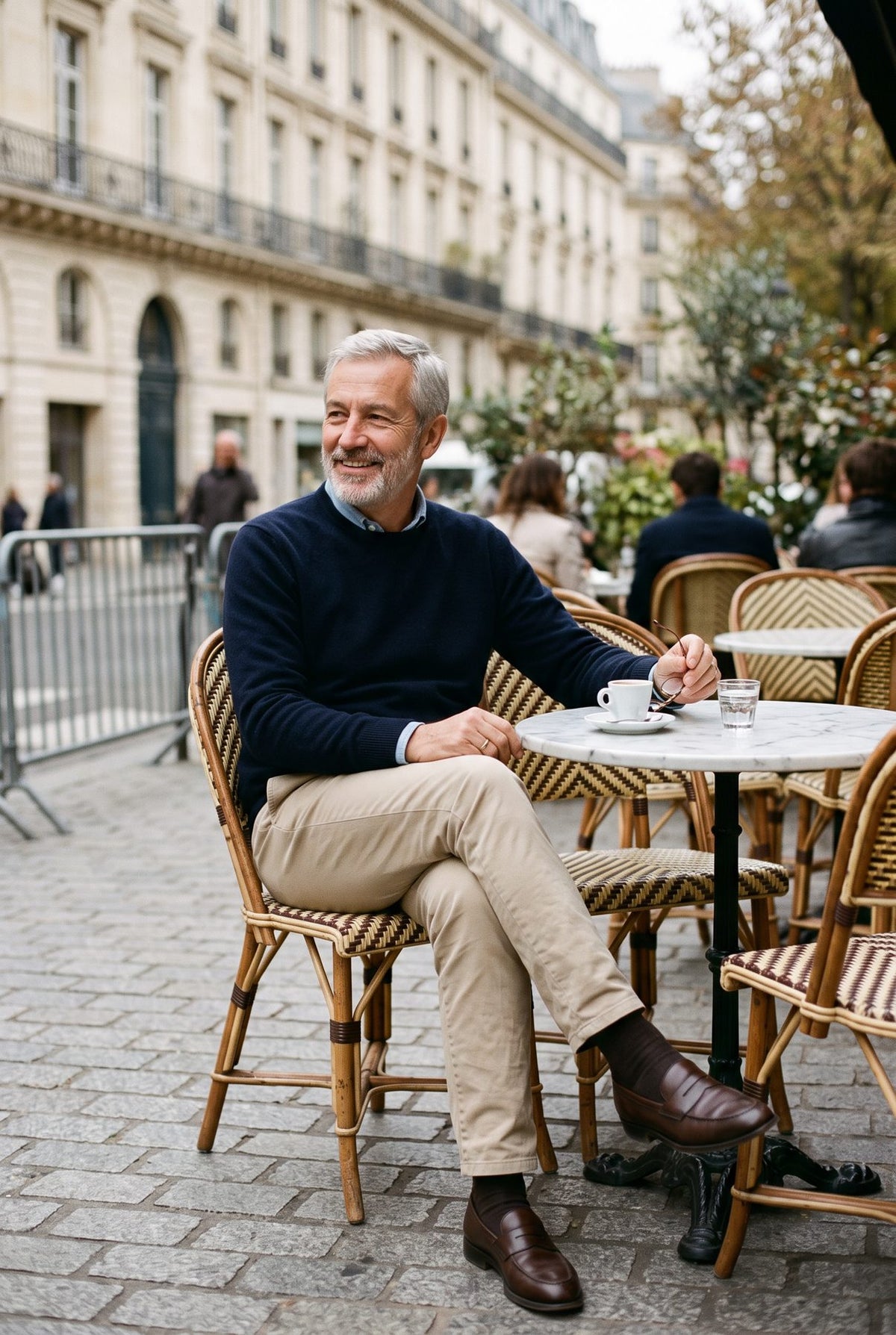 Homme élégant assis à une terrasse de café parisien en pull marine